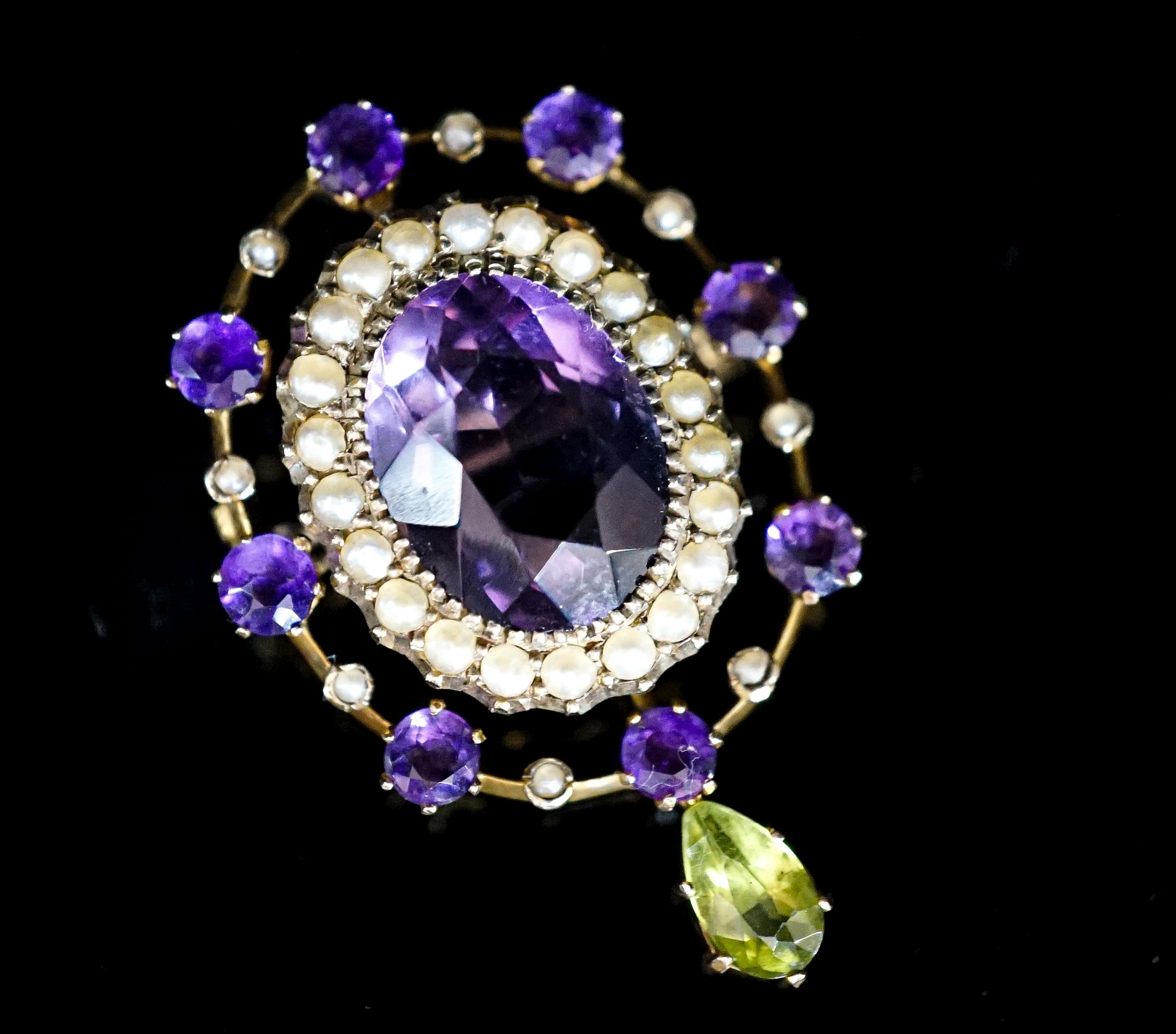 An early 20th century yellow metal, amethyst and peridot set drop oval brooch, in the suffragette colours, 35mm, gross weight 4. 6 grams.